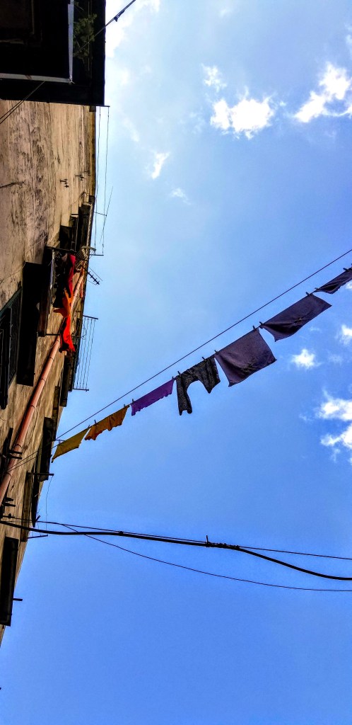 Laundry drying on a clothes line against a blue sky in Naples, Italy.