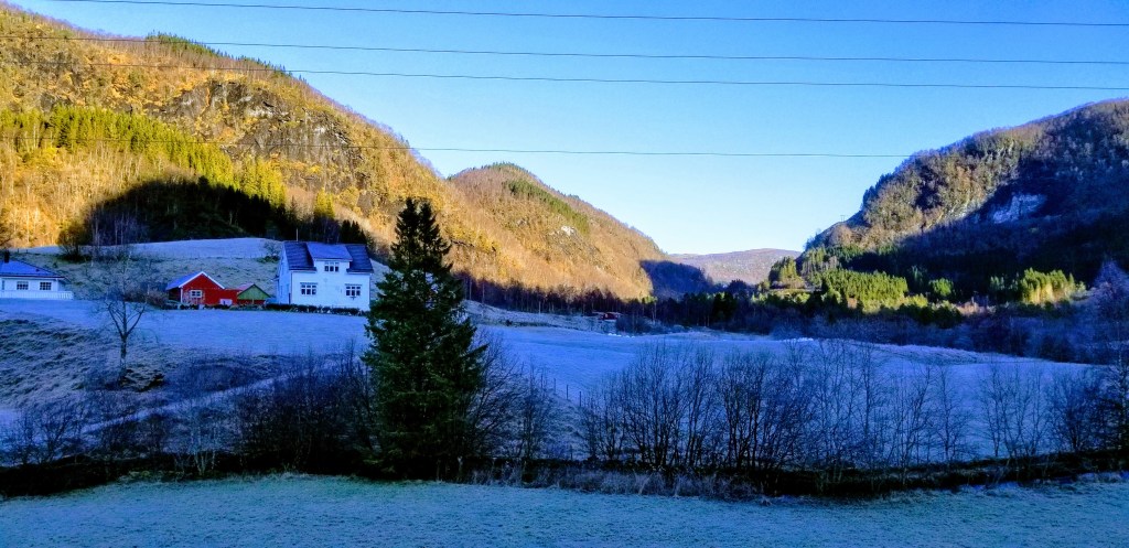 Landscape shot of hilly farmland, frosted over in the shadowy places.