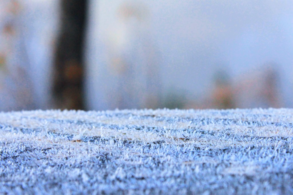 Closeup of frost crystals on a fence post.
