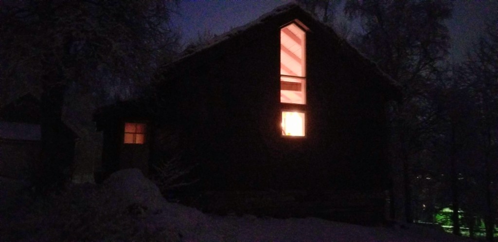 A brightly-lit house against a dark sky.