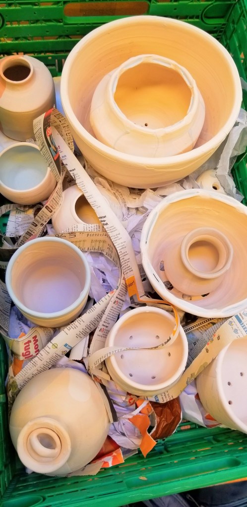 Photograph of unfired ceramic pottery in a crate.