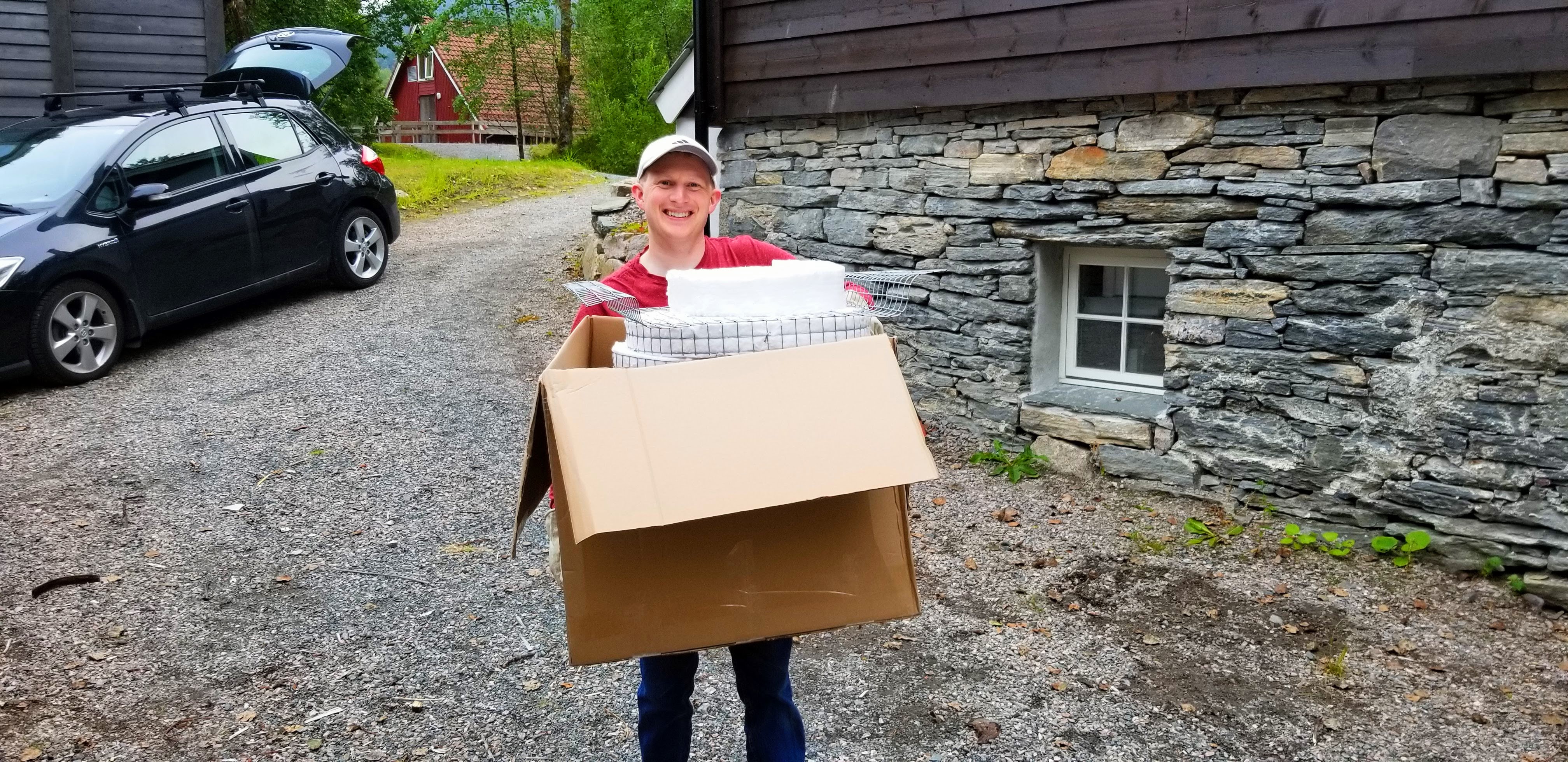 Photograph of a person carrying a raku kiln in a box.
