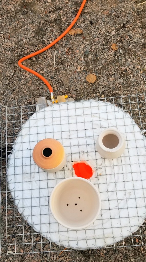 Photograph of three ceramic pots on top of a hot raku kiln.