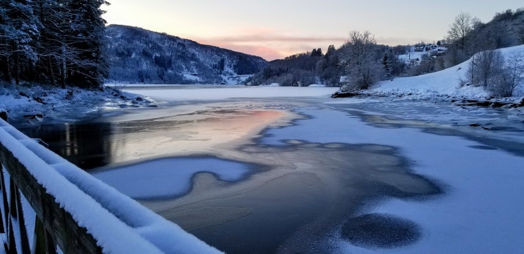 Photograph of a frozen fjord reflecting the sunset.