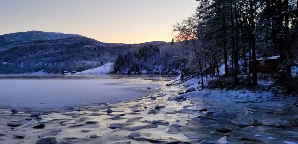 Photograph of a frozen fjord where ice has cracked and heaved up in the tide.