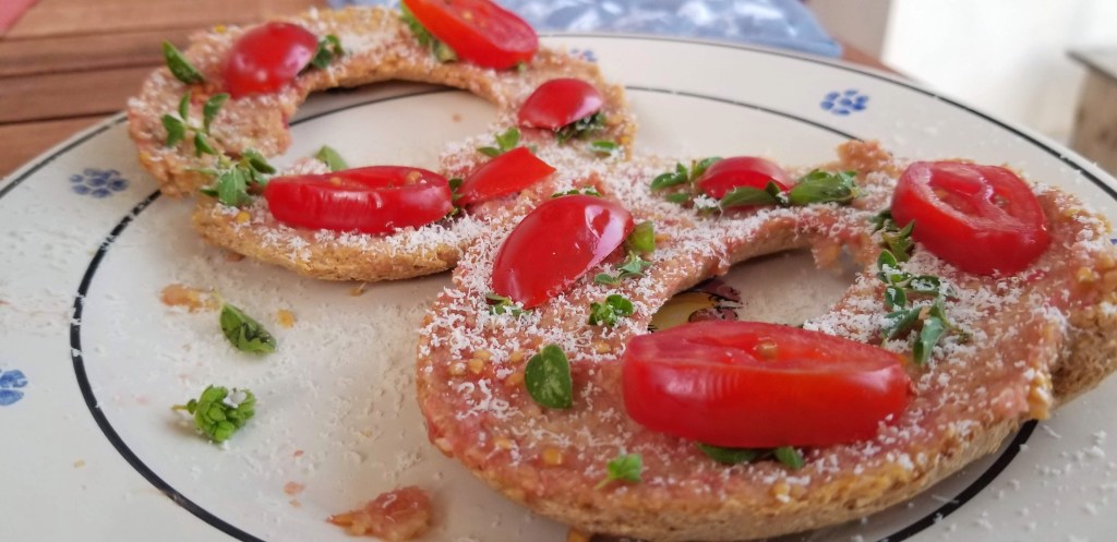 Photograph of two frise (Puglian dry bread) with tomatoes and herbs.