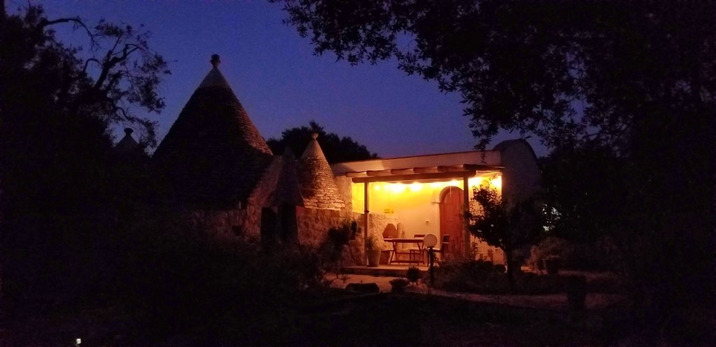 Photograph of a stone trullo house at night.